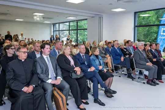 Grupa ludzi siedzących na sali konferencyjnej podczas wydarzenia.