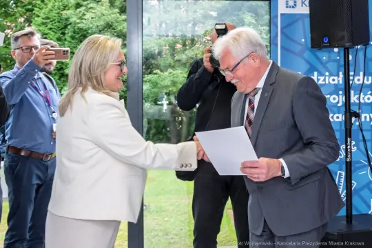 Uścisk dłoni między dwiema osobami podczas wręczenia dokumentu.