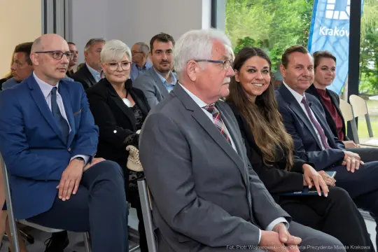Grupa ludzi siedzących w sali, uczestniczących w wydarzeniu.