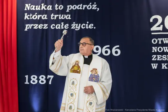 Kapłan w szatach liturgicznych trzyma kropidło podczas ceremonii otwarcia.