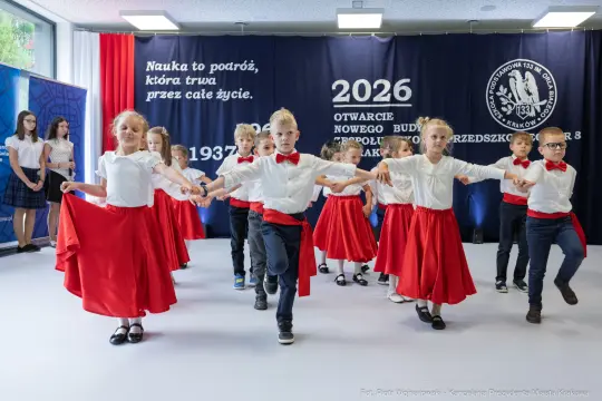 Dzieci w strojach tanecznych wykonują układ taneczny na scenie.