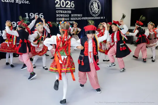 Dzieci w tradycyjnych strojach ludowych tańczą podczas otwarcia nowego budynku szkoły.