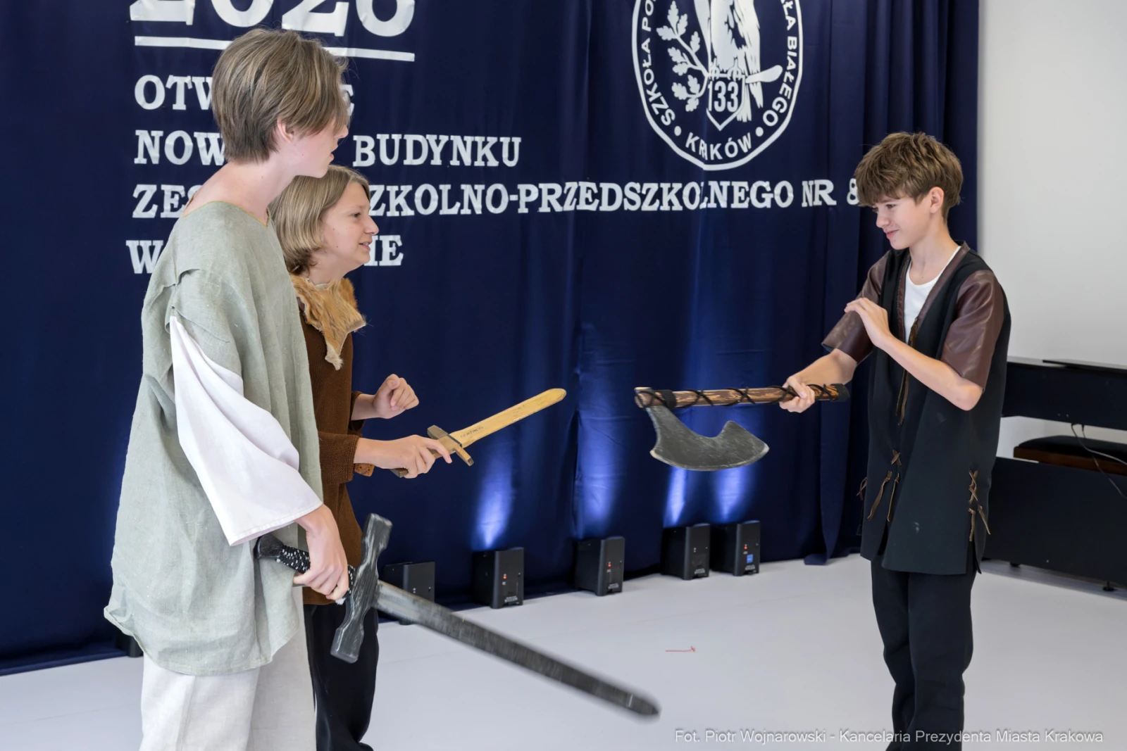 Trzej młodzi ludzie w strojach historycznych, trzymające miecze i topór, w trakcie inscenizacji.  Autor: Piotr Wojnarowski