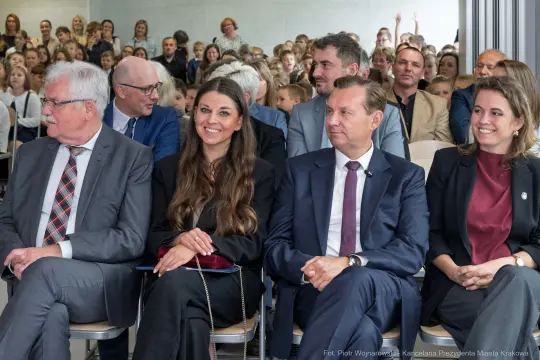 Grupa ludzi siedzących na sali, uczestniczących w wydarzeniu.