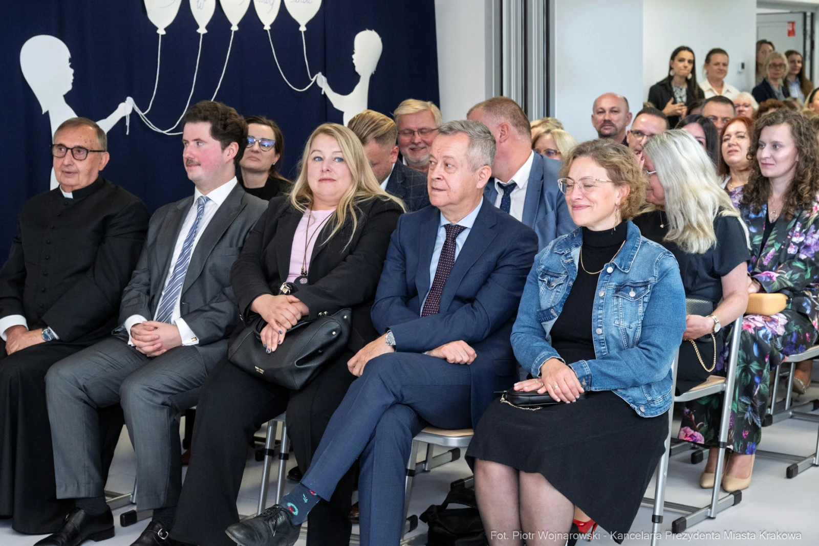 Grupa osób siedzących na wydarzeniu, w tle dekoracja z balonami.  Autor: Piotr Wojnarowski
