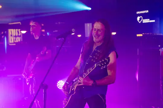 Muzyk grający na gitarze elektrycznej podczas koncertu w oświetleniu sceny.