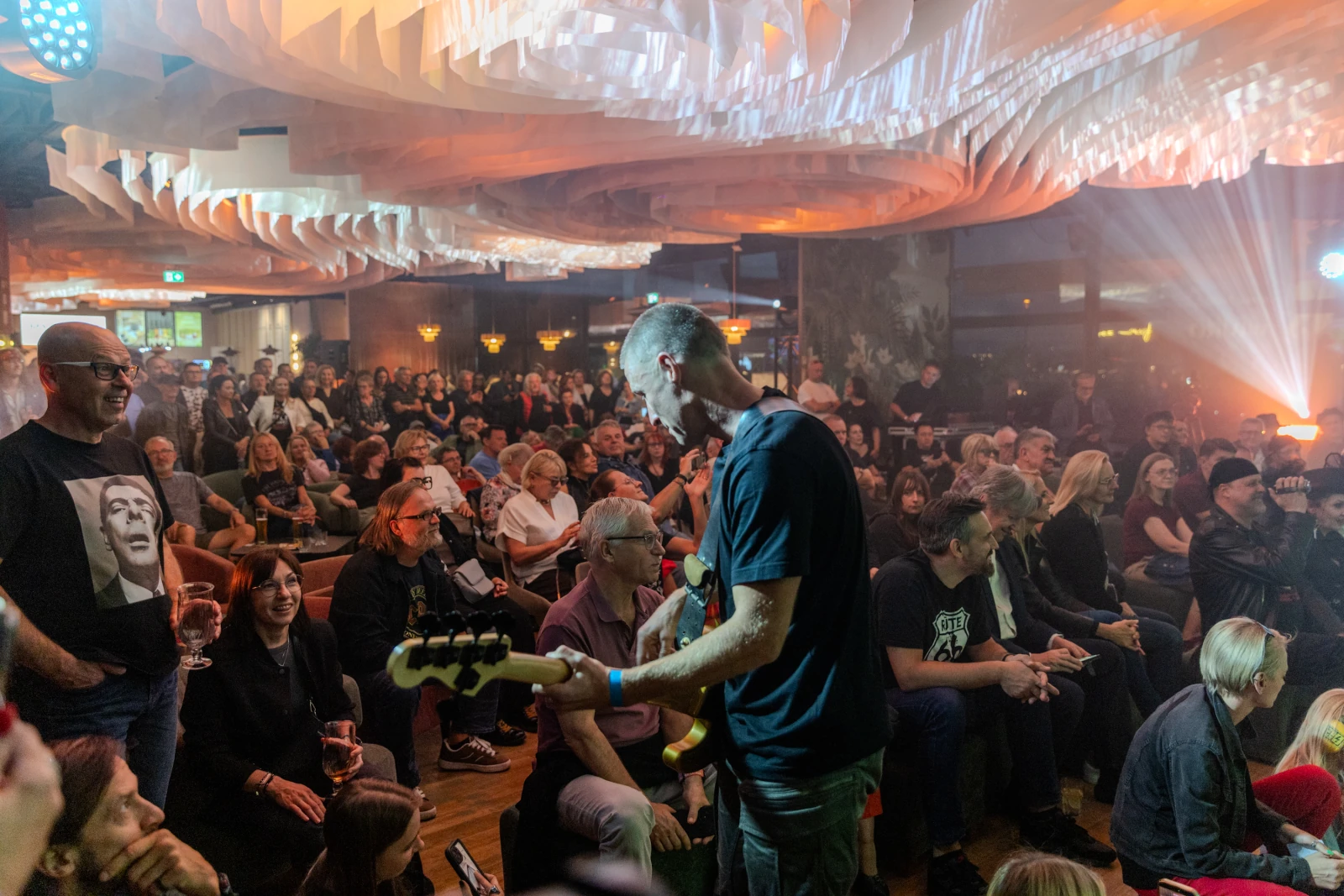 Muzyk grający na gitarze basowej przed tłumem w klubie muzycznym.  Autor: Bogusław Świerzowski