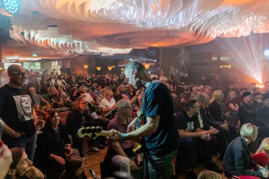 Muzyk grający na gitarze basowej przed tłumem w klubie muzycznym.