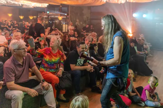 Muzyk grający na gitarze przed publicznością w klubie.