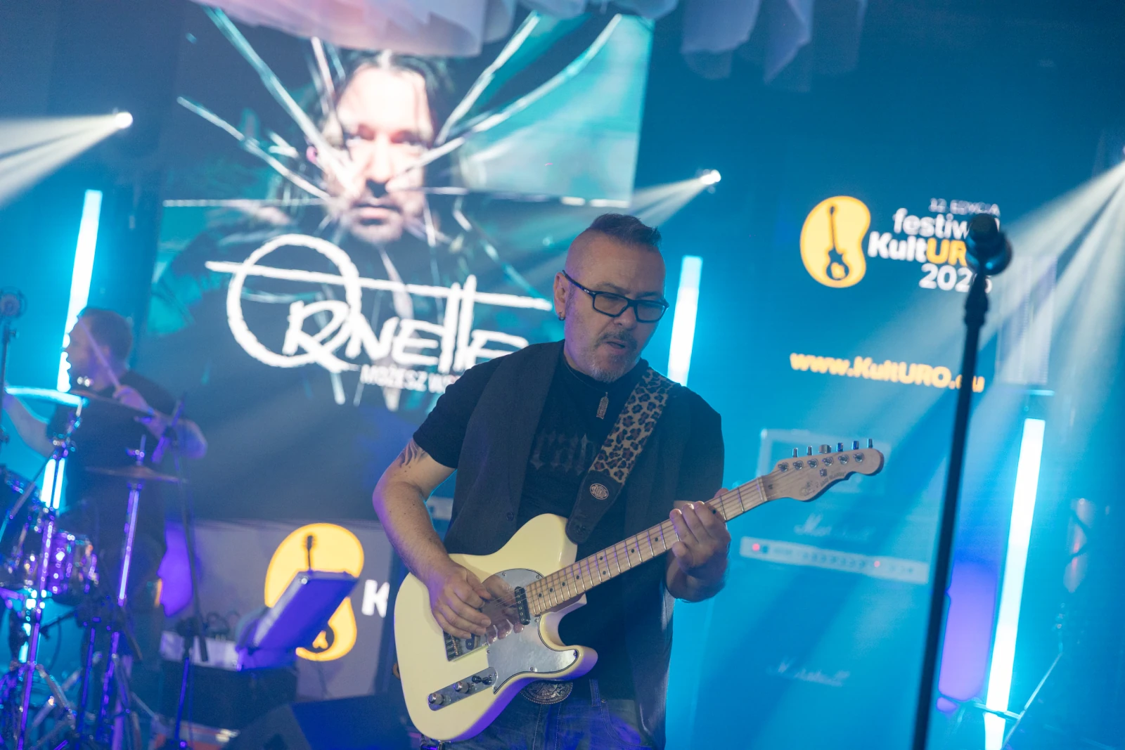 Muzyk grający na gitarze elektrycznej podczas koncertu z efektami świetlnymi w tle.  Autor: Bogusław Świerzowski