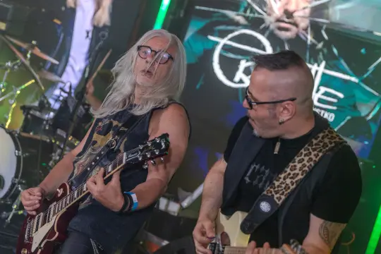 Muzycy grający na gitarach podczas występu na scenie.