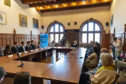 Spotkanie w sali konferencyjnej z uczestnikami i prelegentami przy stole.