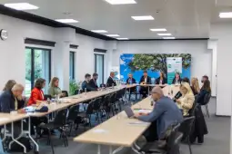 Spotkanie w sali konferencyjnej z uczestnikami przy długim stole.