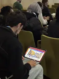 Mężczyzna siedzący na krześle, pracujący na laptopie z otwartą stroną internetową.