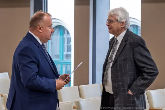 Dwaj mężczyźni rozmawiają w sali konferencyjnej.