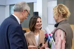 Trzy osoby rozmawiają w biurze, jedna z nich trzyma dokumenty.