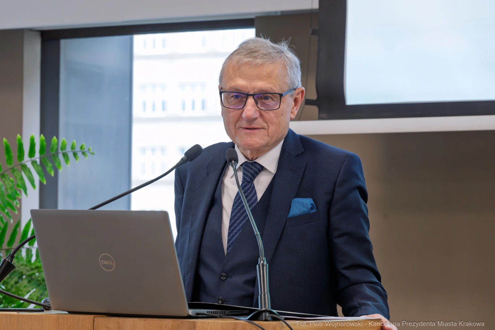 Mężczyzna w okularach stoi przy mównicy, obok laptopa, wygłasza przemówienie.  Autor: Piotr Wojnarowski