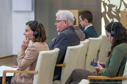 Uczestnicy konferencji w trakcie dyskusji, niektórzy z słuchawkami.