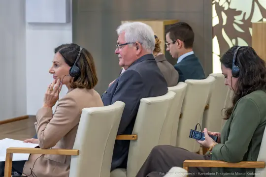 Uczestnicy konferencji w trakcie dyskusji, niektórzy z słuchawkami.