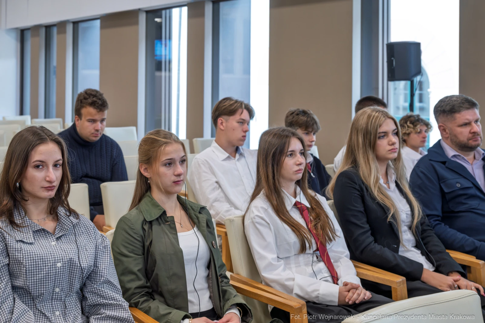 Grupa młodych ludzi i dorosłych siedzących w sali konferencyjnej.  Autor: Piotr Wojnarowski