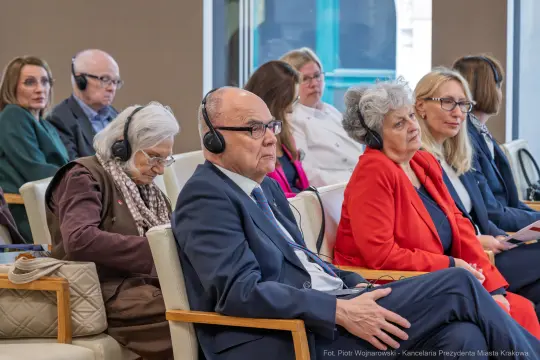 Grupa osób w słuchawkach, uczestniczących w wydarzeniu lub konferencji.