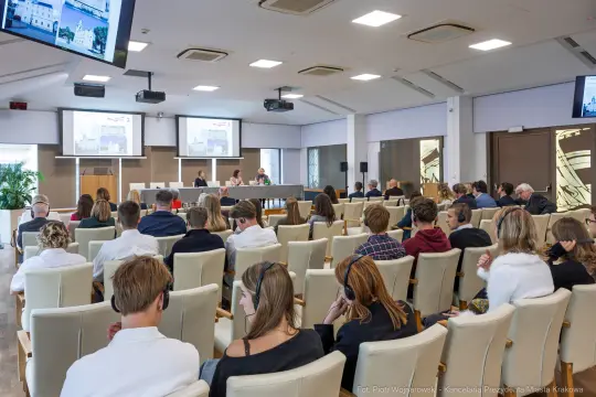 Spotkanie w sali konferencyjnej z uczestnikami siedzącymi w rzędach.