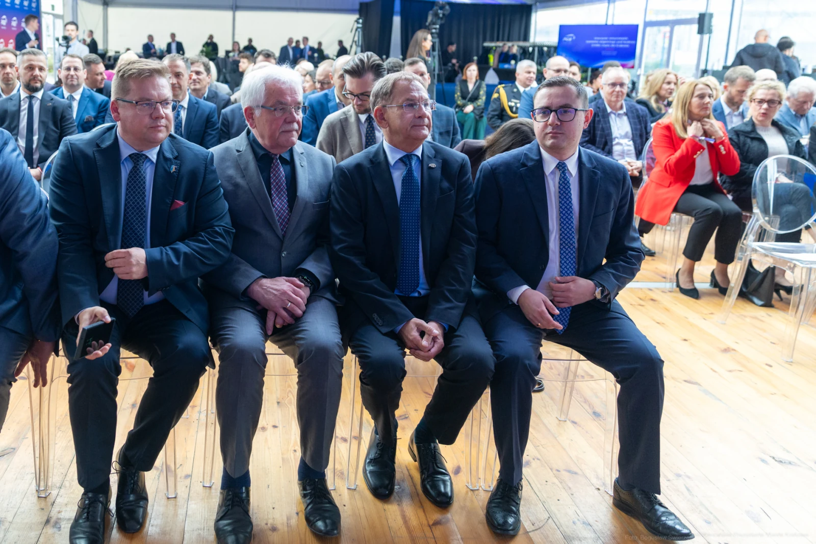 Czterech mężczyzn w garniturach siedzących na widowni podczas wydarzenia.  Autor: Bogusław Świerzowski