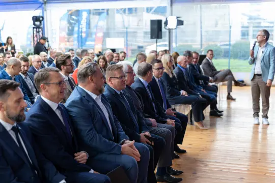 Grupa mężczyzn w garniturach siedzących na widowni podczas wydarzenia.