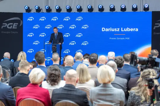 Dariusz Lubera przemawia na konferencji PGE, w tle logo firmy i zgromadzeni goście.