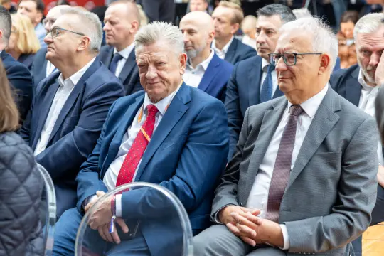 Grupa mężczyzn w garniturach siedzących na wydarzeniu.