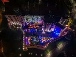 Widok na oświetloną nocą architekturę z kolorowymi światłami i zorganizowanym wydarzeniem na świeżym powietrzu.