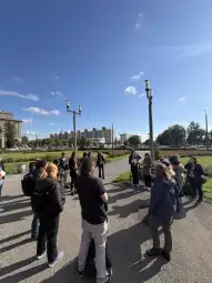 Grupa ludzi w parku, rozmawiających ze sobą w słoneczny dzień.