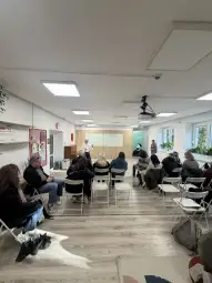Spotkanie w sali z uczestnikami siedzącymi na krzesłach, prelegent przy tablicy.
