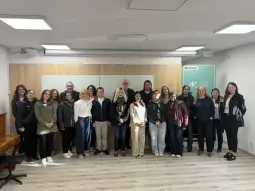 Grupa ludzi stojąca w sali, uśmiechająca się do aparatu.