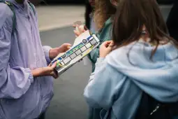 Grupa osób trzymająca model autobusu w kolorowej grafice.