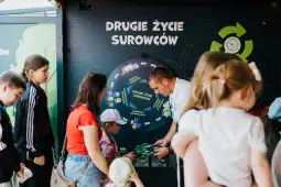Edukacyjna wystawa o recyklingu z dziećmi i dorosłymi przy interaktywnym kole.