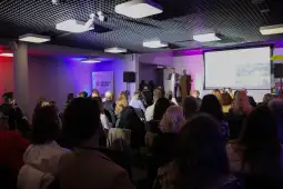 Konferencja z prelegentem na scenie i publicznością siedzącą w sali.