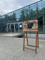 Stojak z cegłami przed nowoczesnym budynkiem.