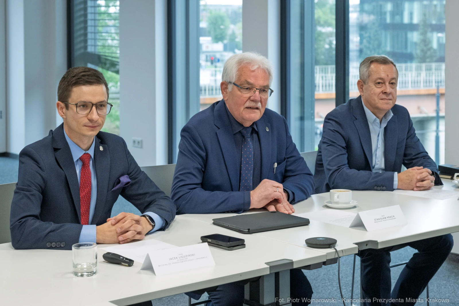Trzech mężczyzn siedzących przy stole, prowadzących dyskusję w nowoczesnym biurze.  Autor: Piotr Wojnarowski