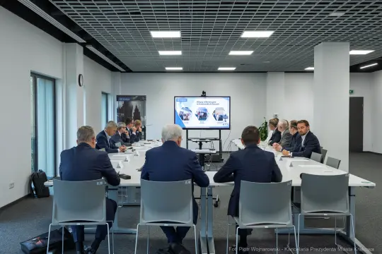 Spotkanie biznesowe w nowoczesnej sali konferencyjnej z prezentacją na ekranie.