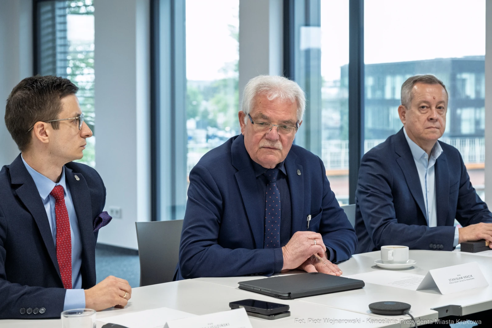 Trzech mężczyzn w garniturach siedzi przy stole w sali konferencyjnej.  Autor: Piotr Wojnarowski
