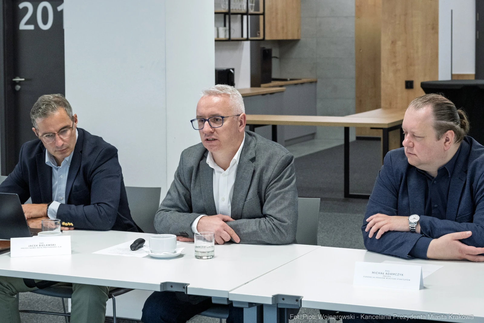 Trzech mężczyzn w trakcie dyskusji przy stole w nowoczesnym biurze.  Autor: Piotr Wojnarowski