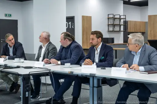 Spotkanie grupy mężczyzn przy stole konferencyjnym w nowoczesnym wnętrzu.