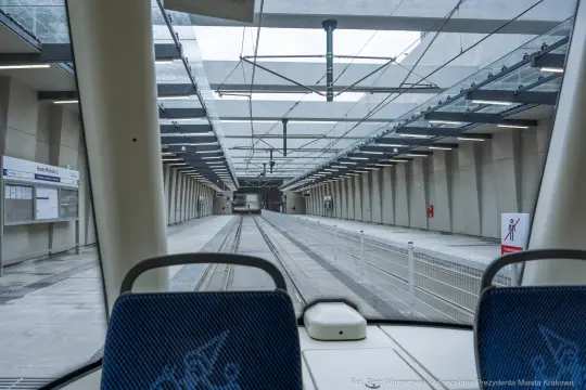 Wnętrze stacji kolejowej z widokiem na tory i peron.