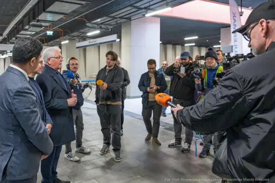Konferencja prasowa z udziałem kilku mężczyzn i dziennikarzy w nowoczesnym wnętrzu.