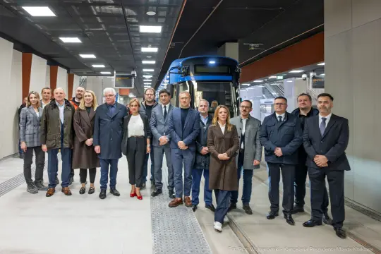 Grupa ludzi pozująca przy nowym tramwaju w Krakowie.