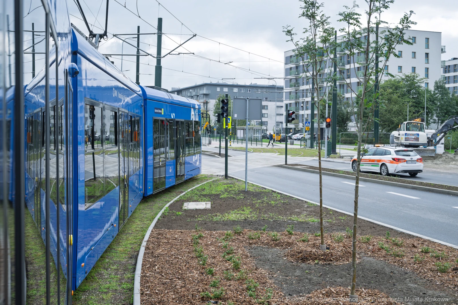 Niebieski tramwaj skręcający w ulicę, obok nowe budynki i sygnalizacja świetlna.  Autor: Piotr Wojnarowski