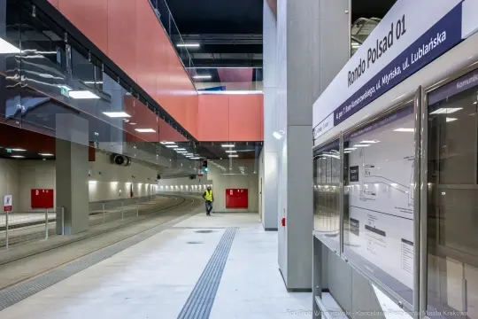 Nowoczesna stacja tramwajowa z torami i tablicą informacyjną.