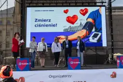 Kobiety i mężczyzna na scenie podczas wydarzenia zdrowotnego z hasłem o mierzeniu ciśnienia.