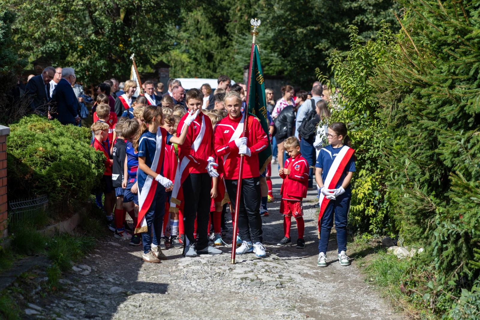 Grupa dzieci w strojach sportowych z flagami, idąca w procesji.  Autor: Bogusław Świerzowski